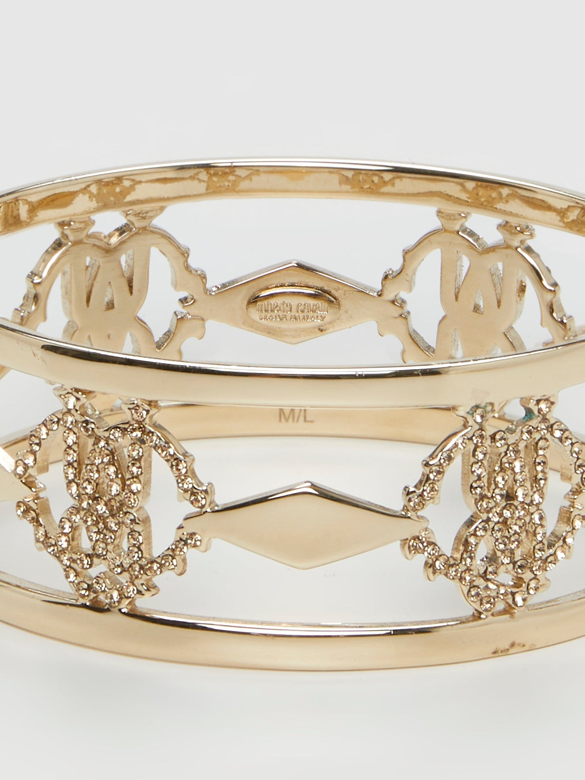 Introducing the luxurious Gold Logo Bangle by the esteemed Roberto Cavalli ��� a true masterpiece for the fashion connoisseurs. Crafted with utmost precision, this exquisite accessory showcases an iconic logo motif beautifully engraved in gold, reflecting elegance and sophistication. Elevate your style and make a bold statement with this dazzling bangle, commanding attention from every angle.